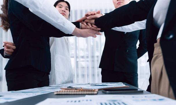 Closeup business team of suit-clad businessmen and women join hand stack together and form circle. Colleague collaborate and work together to promote harmony and teamwork concept in office workplace. - Foto, afbeelding