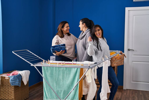 Három nő ruhákat lóg a ruhaszárítón és táncol a mosodában. - Fotó, kép