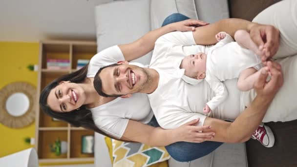 Famiglia di tre persone sedute sul divano di casa - Filmati, video