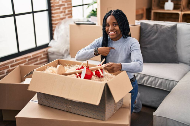 African american woman moving to a new home opening boxes pointing finger to one self smiling happy and proud  - Fotoğraf, Görsel