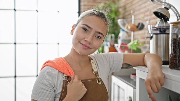 Young beautiful hispanic woman wearing apron smiling confident at dinning room - Photo, Image