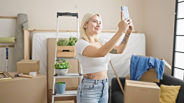 Junge schöne hispanische Frau macht Selfie per Smartphone im neuen Zuhause - Foto, Bild