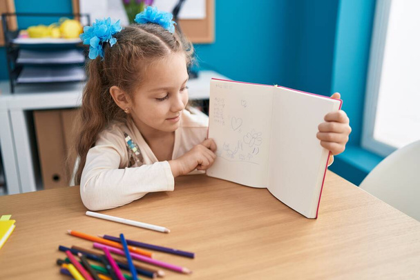 Suloinen valkoihoinen tyttö osoittaa piirtää istuu pöydällä toimistossa - Valokuva, kuva
