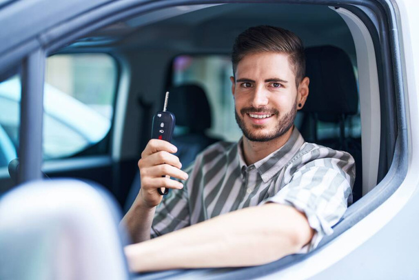 Молодий білий чоловік посміхається впевнено тримає ключ від нової машини на вулиці
 - Фото, зображення
