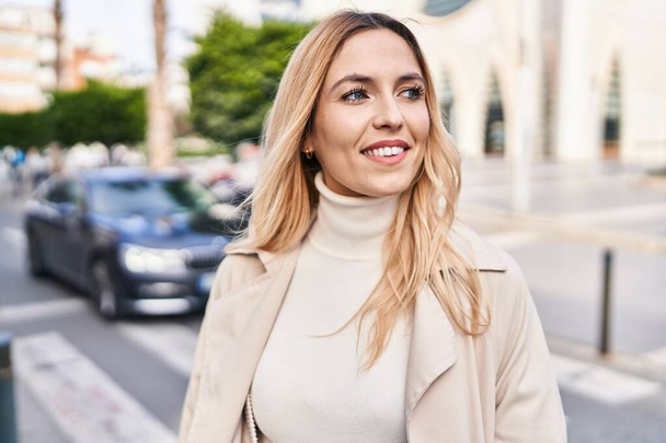 Young blonde woman smiling confident looking to the side at street - Fotoğraf, Görsel