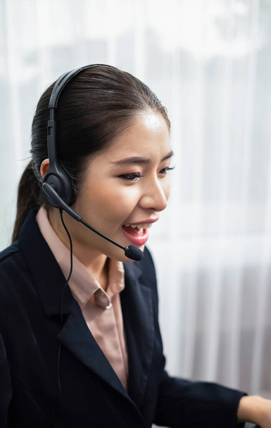 Bilgisayarında mikrofon ve kulaklıkla Asyalı çağrı merkezi çalışıyor. Kadın operatör istisnai müşteri hizmetleri sunar. Destek veren çağrı merkezi ajanı, müşteriye soruşturmada yardım ediyor. Coşkulu. - Fotoğraf, Görsel