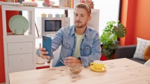 Молодий білий чоловік сніданок робить відеодзвінок у їдальні - Кадри, відео