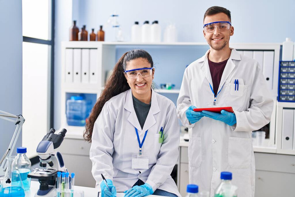 Man and woman wearing scientist uniform using touchpad write on document at laboratory - Foto, imagen