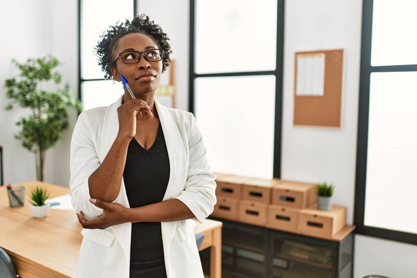 Femme afro-américaine ouvrière d'entreprise debout avec l'expression du doute au bureau - Photo, image