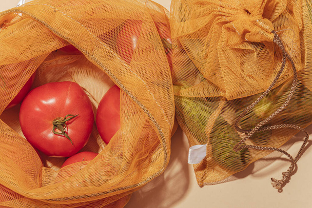 Bolsas reutilizables para comprar verduras y frutas. Bolsas con tomates y pepinos. Cuidado ecológico, consumo consciente, cuidado de la naturaleza. Día Mundial del Reabastecimiento - Foto, Imagen