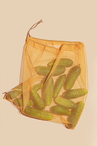 Огурцы хранятся в экологически чистой сумке, способствуя сознательному и устойчивому использованию. Этот образ представляет важность экологически сознательного выбора и поощряет ответственное поведение потребителей - Фото, изображение