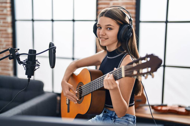 Очаровательная девушка-музыкант поет песню классической гитары в музыкальной студии - Фото, изображение
