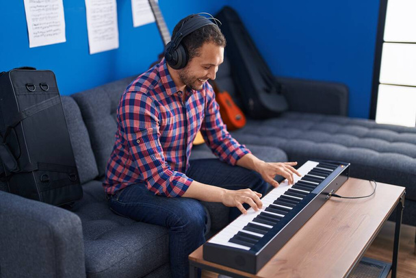 Young man musician playing piano keyboard at music studio - Foto, afbeelding