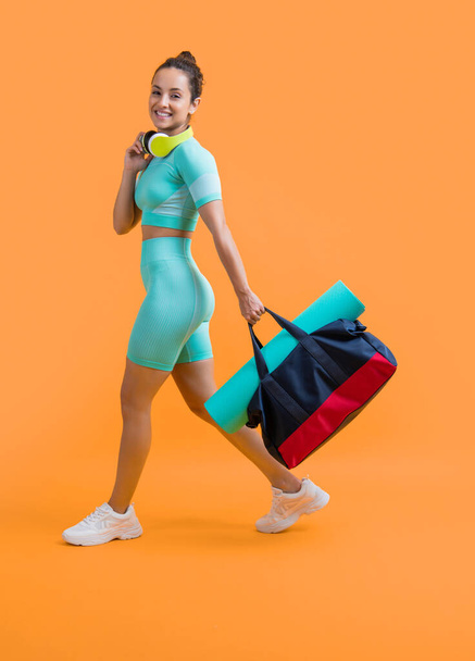 fitness sportswoman in sportswear walk with sport bag in studio. fitness sportswoman in workout sportswear isolated on yellow background. fitness and sportswear. - Photo, image