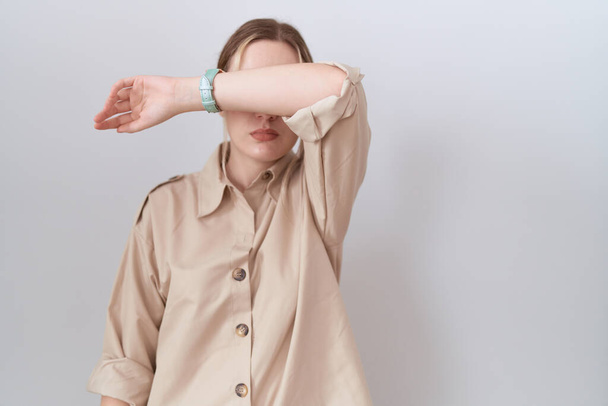 Young caucasian woman wearing casual shirt covering eyes with arm, looking serious and sad. sightless, hiding and rejection concept  - Foto, afbeelding