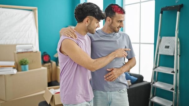 Δύο άνδρες ζευγάρι κοιτάζοντας γύρω μιλώντας στο νέο σπίτι - Φωτογραφία, εικόνα
