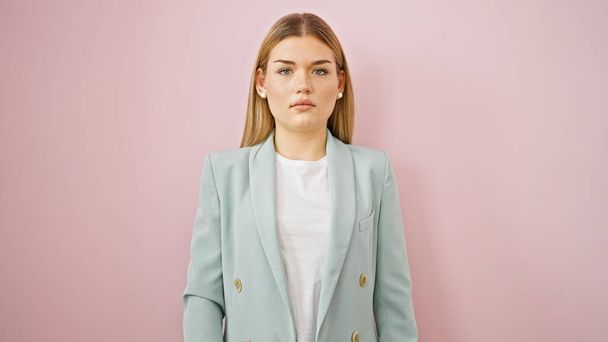 Nuori blondi nainen liiketoiminnan työntekijä seisoo vakavat kasvot yli eristetty vaaleanpunainen tausta - Valokuva, kuva