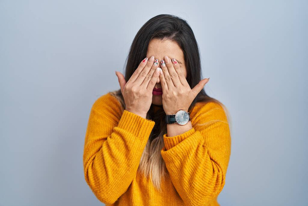 Молода іспаномовна жінка стоїть над ізольованим тлом, натираючи очі на втому і головний біль, сонний і втомлений вираз. проблема зір
  - Фото, зображення