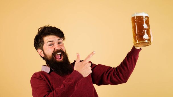 Kaljapubi. Oluen aika. Emotionaalinen parrakas mies, joka osoittaa sormella olutmukia. Panimo. Tyylikäs komea mies juo olutta juhlissa. Mies maistelee kylmää olutta. Oktoberfest-festivaalit. Alkoholi, vapaa-aika - Valokuva, kuva