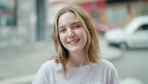 Молодая белая женщина улыбается уверенно стоя на улице - Фото, изображение