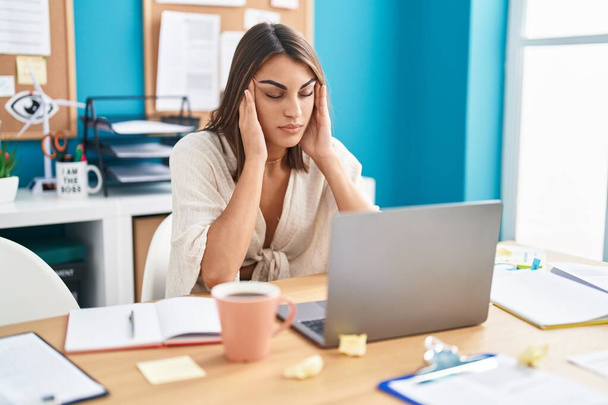 Jonge mooie Spaanse vrouw zakenman gestrest met behulp van laptop op kantoor - Foto, afbeelding