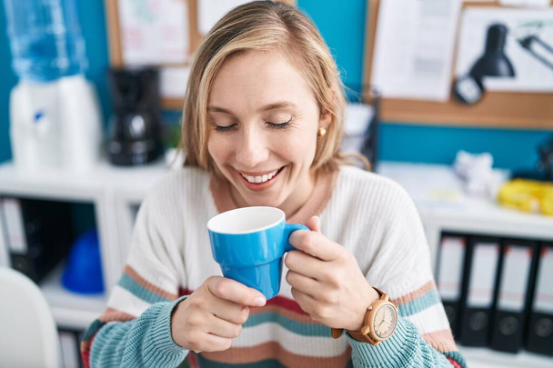 Jovem loira mulher empresária sorrindo confiante beber café no escritório - Foto, Imagem