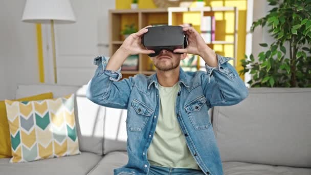 Young caucasian man playing video game using virtual reality glasses at home - Metraje, vídeo