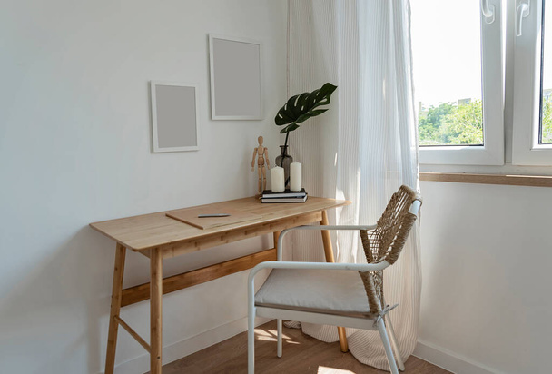 Design interior of room with office table and chair near window. Office room with wooden furniture and blank frame on the wall. New apartment. - Foto, Imagem