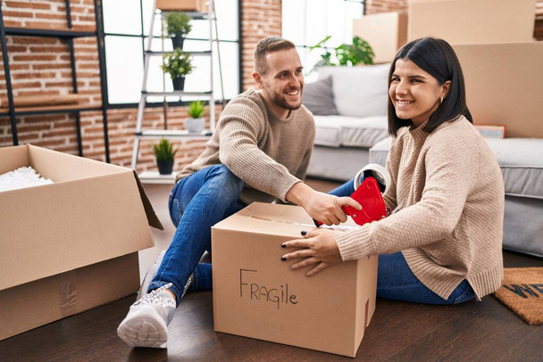 Homme et femme couple emballage boîte en carton fragile à la nouvelle maison - Photo, image