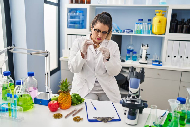 Молодая красивая женщина-ученый, держащая гриб с пинцетом в аптеке - Фото, изображение