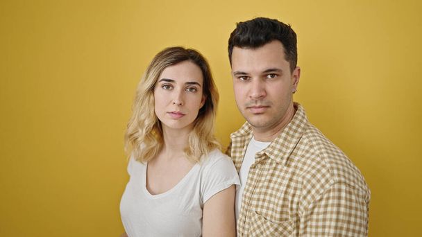 Kadın ve erkek, izole edilmiş sarı arka planda gevşek bir ifadeyle yan yana duruyorlar. - Fotoğraf, Görsel