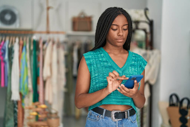 Afrikkalainen amerikkalainen nainen asiakas käyttää älypuhelinta vaatekaupassa - Valokuva, kuva