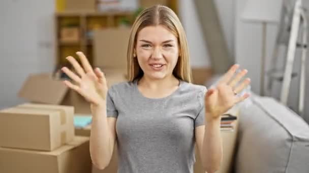 jong blond vrouw glimlachen zelfverzekerd zitten op bank spreken in nieuw huis - Video