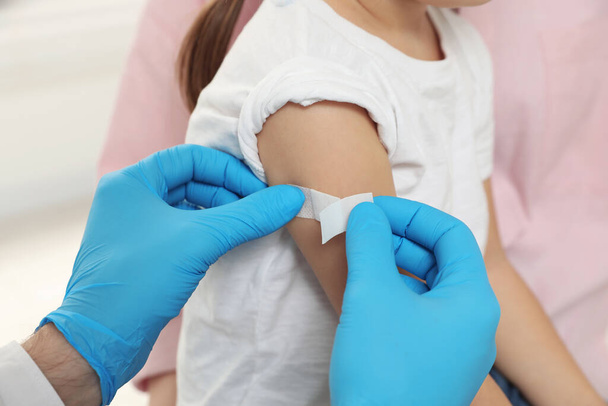 Children's hepatitis vaccination. Mother with her daughter. Doctor sticking medical plaster on little girl's arm, closeup - Fotoğraf, Görsel