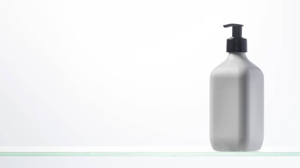 A mockup of a white dispenser with a cosmetic product for skin care of the face and body on a glass shelf. Shower gel, facial cleanser. Copy space. Banner - Foto, Bild