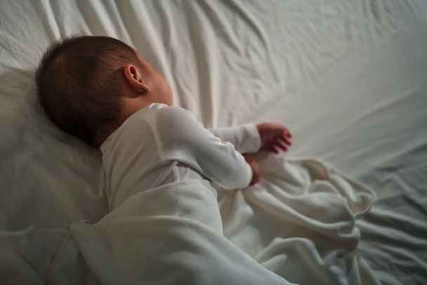 infant baby sleeping on a bed at night - Фото, изображение
