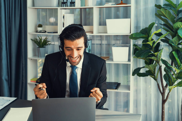 Άντρας τηλεφωνητής ή αντιπρόσωπος telesales που κάθεται στο γραφείο του φορώντας ακουστικά και σε συνομιλία με τον πελάτη που παρέχει υποστήριξη εξυπηρέτησης πελατών ή κάνει πειστική πώληση. έντονος - Φωτογραφία, εικόνα