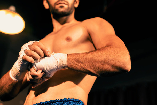 Retrato de boxeador caucásico con cuerpo musculoso y atlético envolviendo su mano o puño en el ring antes del combate de boxeo o entrenamiento. Impulso - Foto, Imagen