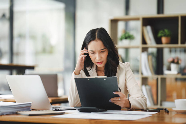 Finansistka, azjatycka kobieta, odczuwa stres pracą, używa laptopa, składa raport firmie finansowej. Księgowość i koncepcja finansowa. - Zdjęcie, obraz