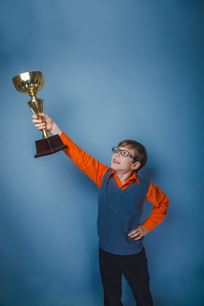 Garçon d'allure européenne de dix ans récompense la joie de la coupe sur un backgr gris
 - Photo, image