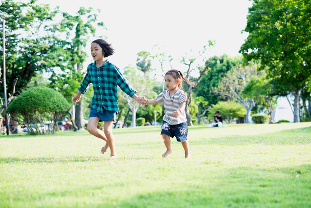 Happy Southeast Asian girls playing outdoors in the spring park. Asian children playing in the garden Summer vacation. - Photo, Image