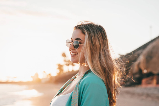 Portrait of one young woman at the beach looking at the sea enjoying free time and freedom outdoors. Having fun relaxing and living happy moments. - Foto, Imagem