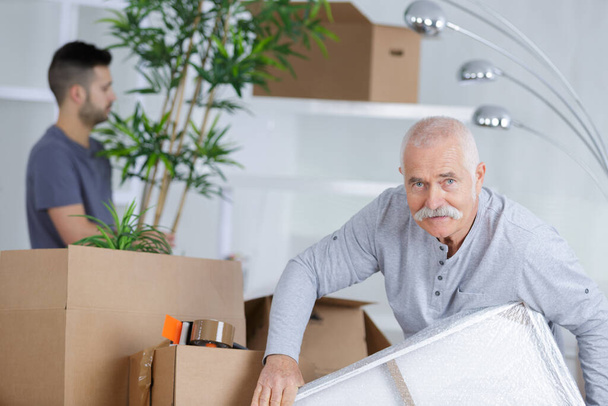 senior man in empty room with packed moving boxes - Fotoğraf, Görsel