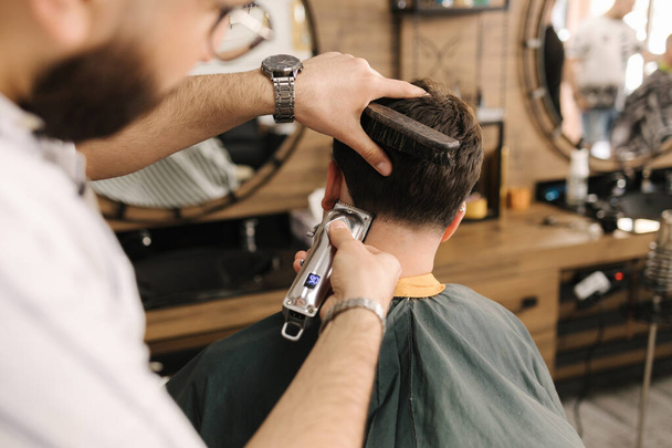 Homem barbudo bonito cortando cabelo de cliente masculino confiante na loja berbere. Foto de alta qualidade - Foto, Imagem