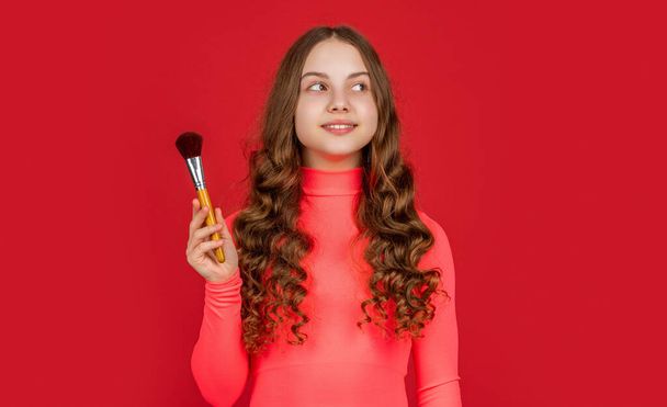 teen makeup. positive kid with curly hair hold powder brush for makeup. - Фото, зображення