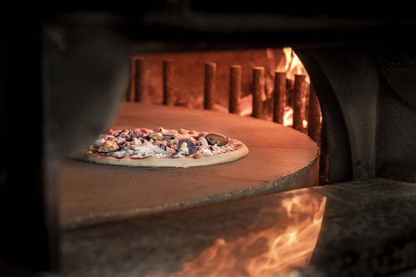 σπιτική πίτσα με φλεγόμενη φωτιά  - Φωτογραφία, εικόνα
