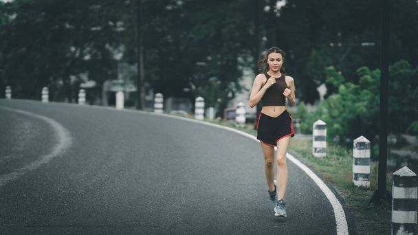 Egészséges ázsiai nő kocog a szabadban. A fitnessz lány fut. Női testmozgás a szabadtéri parkban. - Fotó, kép