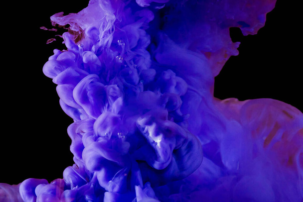 抽象的な旋風、水に紫色のアクリルインクを渦巻く。液滴ペイント水孤立した暗い背景に浮かぶ明るい青紫色のインク煙雲クローズアップ. - 写真・画像