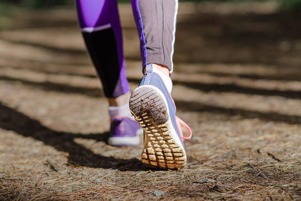 Woman legs in sport shoes walking on dirty road in forest, hiking trip.Walking,running legs in forest,adventure and exercising in summer nature.outdoors activities.Closeup. - Photo, Image