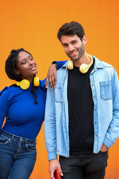 Multietnický pár se sluchátky pózujícími společně na barevném pozadí. Koncept vztahu. - Fotografie, Obrázek